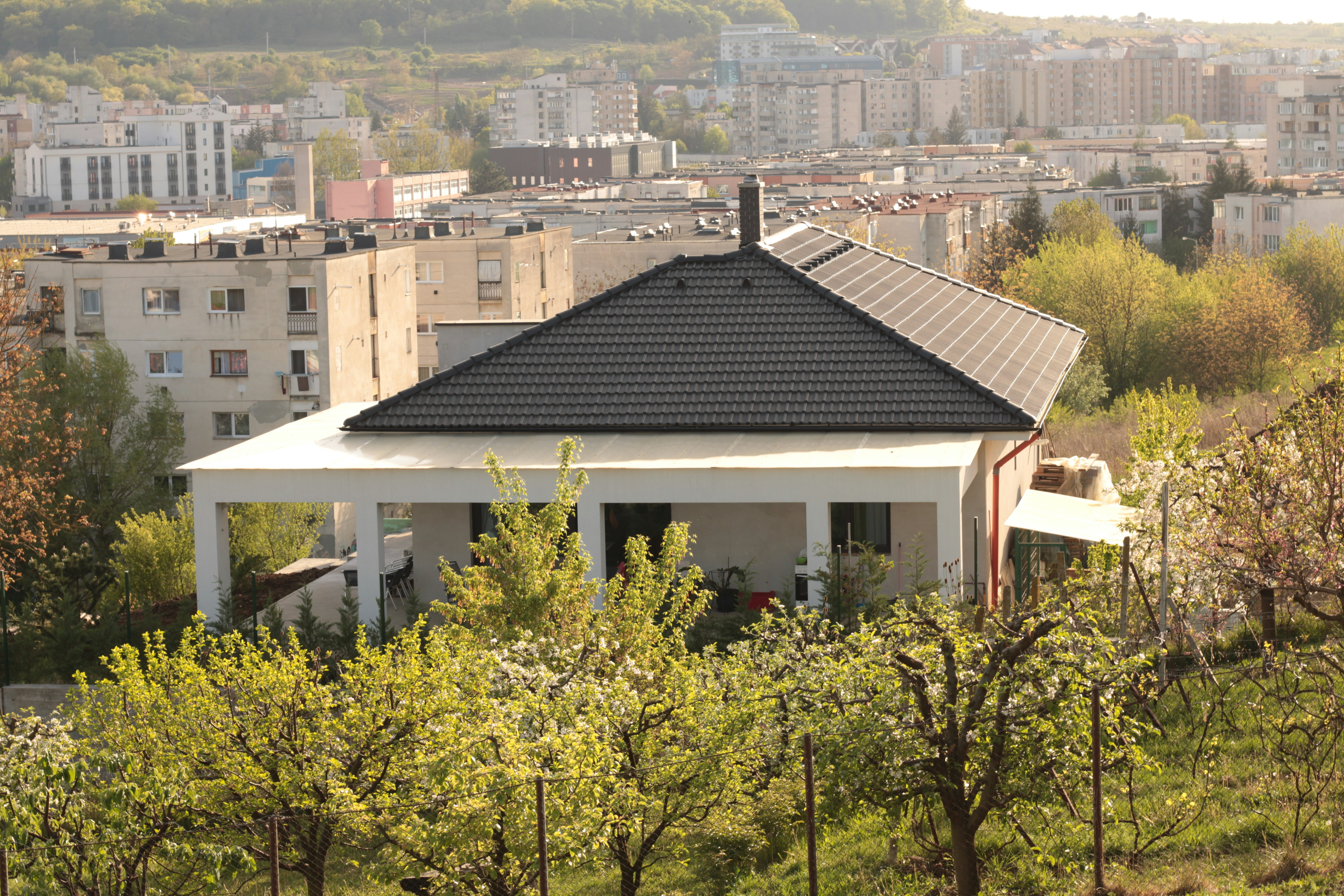 a white house with a black roof surrounded by trees