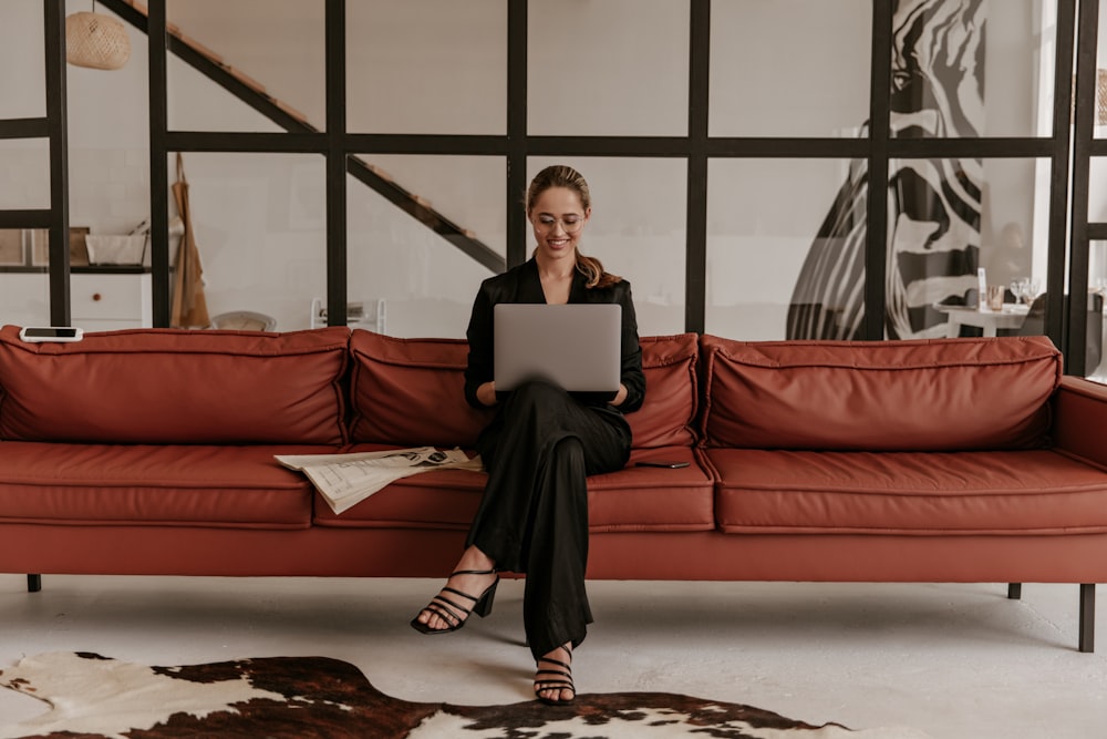 a woman sitting on a couch using a laptop