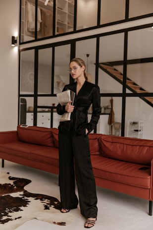 a woman standing in a living room next to a red couch