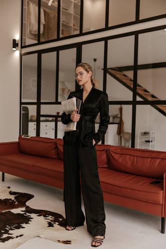a woman standing in a living room next to a red couch