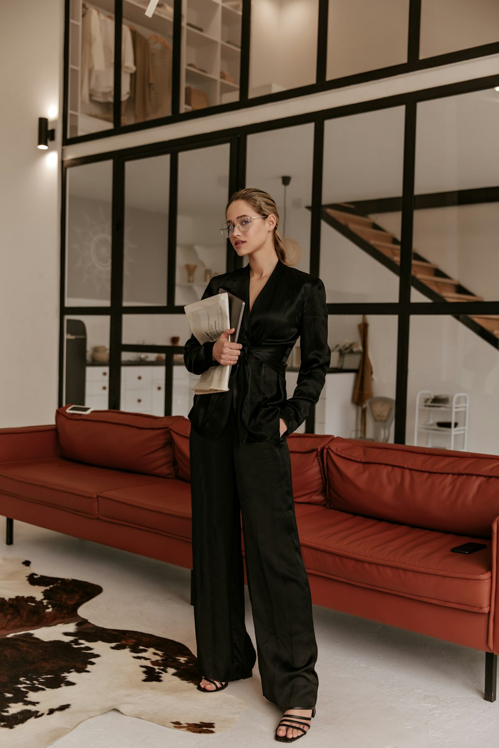 a woman standing in a living room next to a red couch