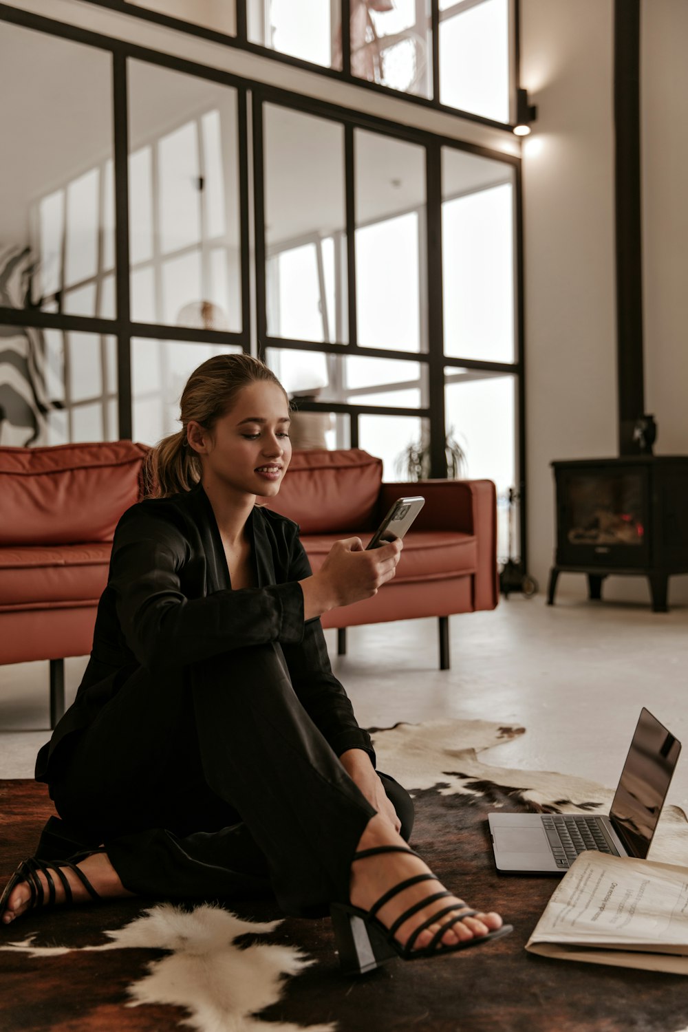 a woman sitting on the floor looking at her cell phone