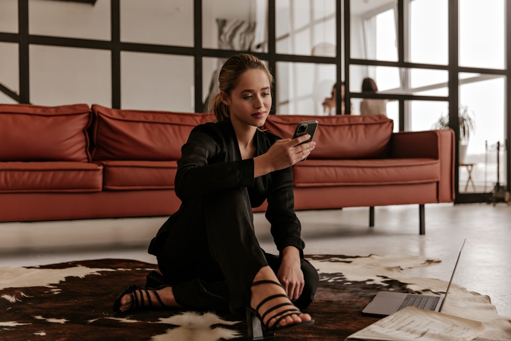 a woman sitting on the floor looking at her cell phone