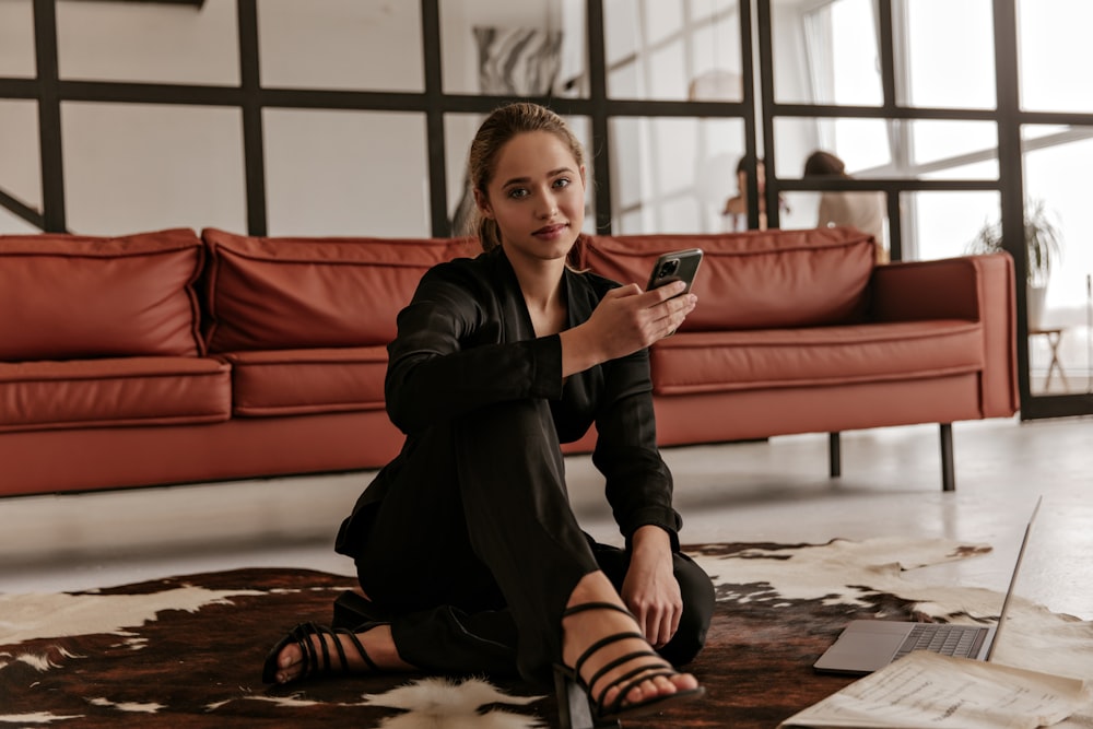 a woman sitting on the floor looking at her cell phone