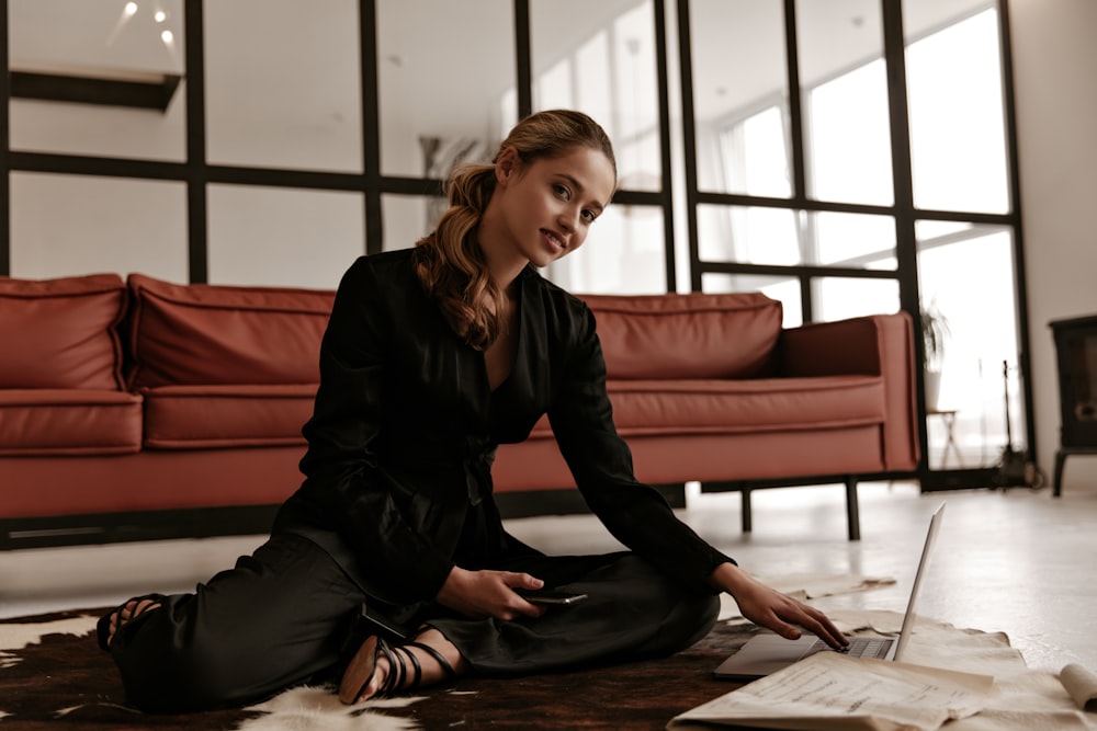 a woman sitting on the floor using a laptop