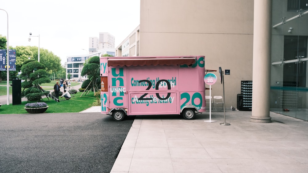a pink food truck parked in front of a building