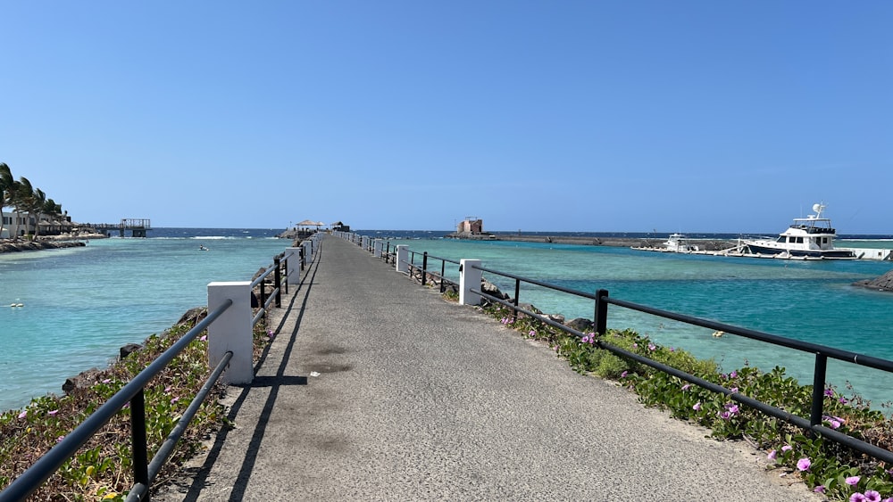 a long walkway leading to a beach with boats in the water