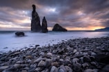 a rocky beach with rocks and water under a cloudy sky