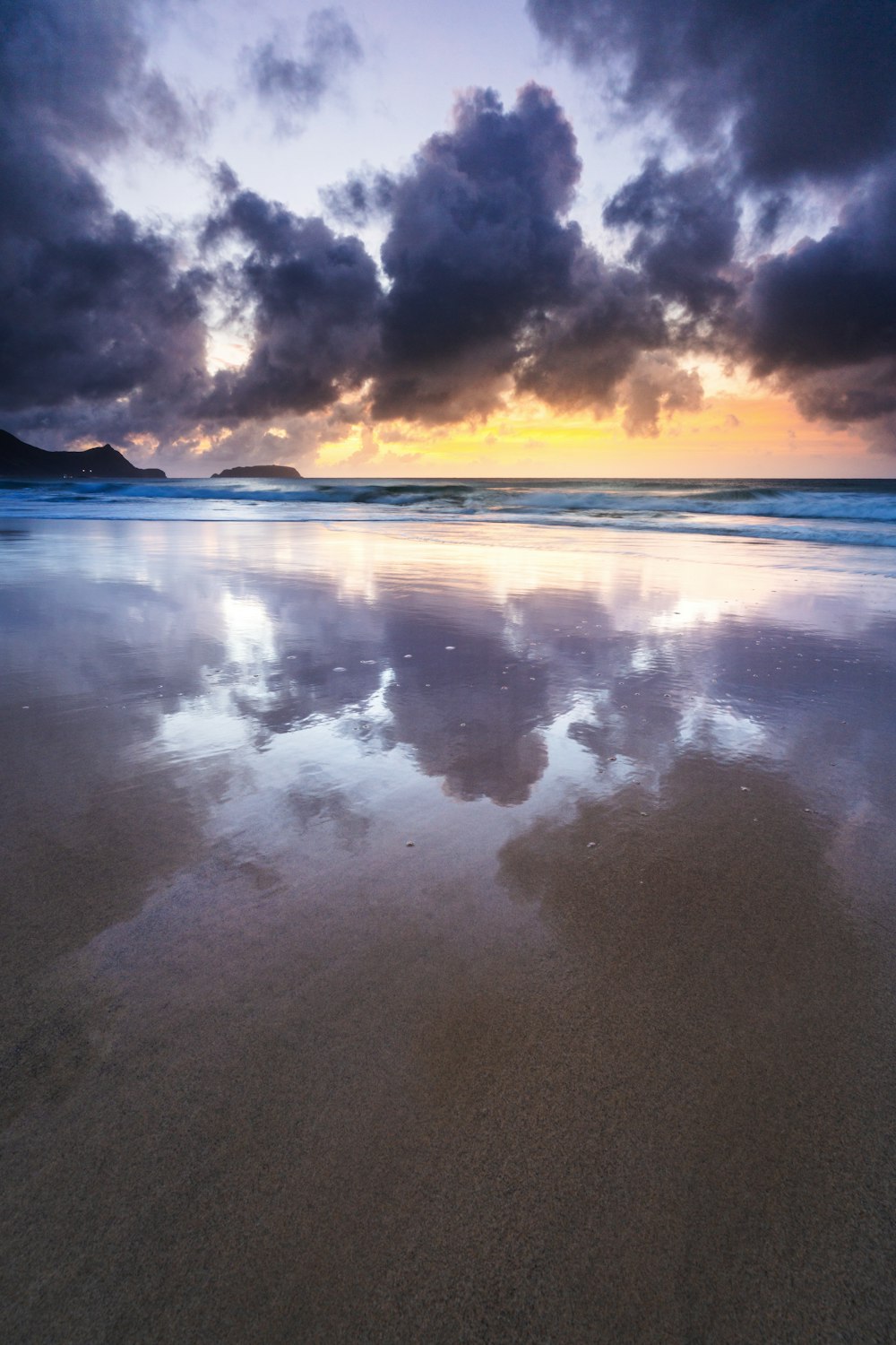 a view of a beach at sunset with clouds in the sky