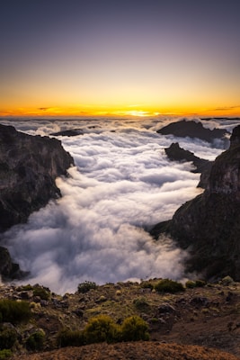 the sun is setting over the clouds in the mountains