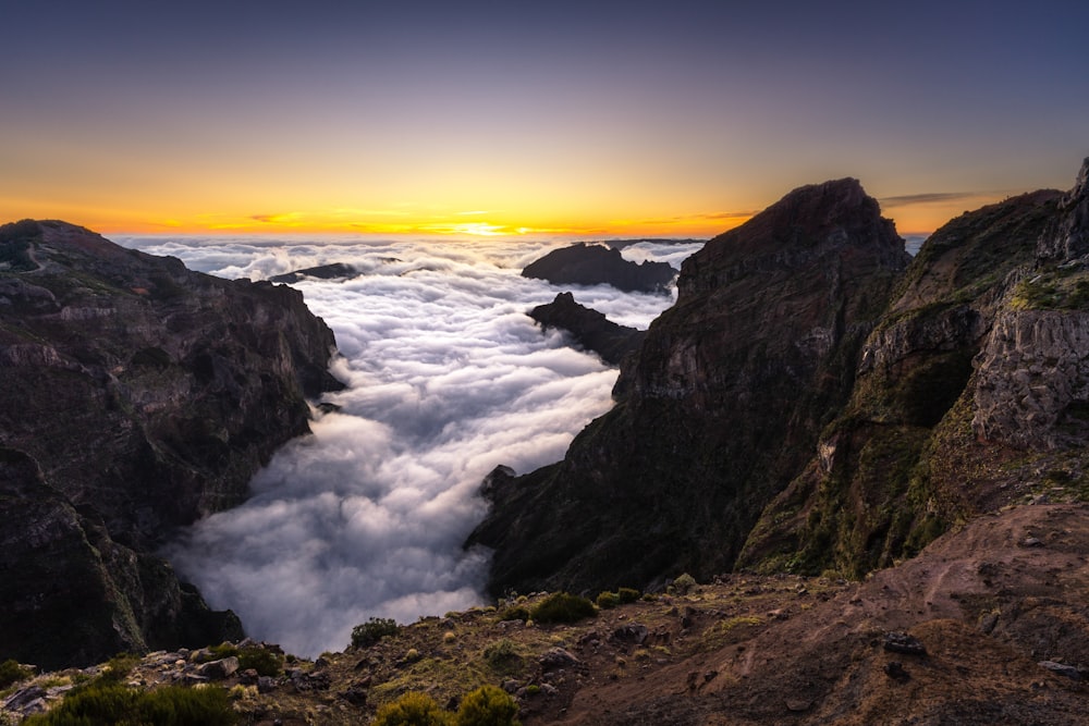 the sun is setting over the clouds in the mountains