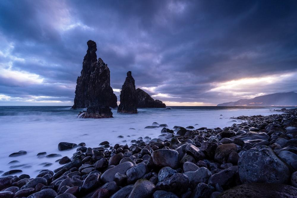 a rocky beach covered in lots of rocks under a cloudy sky