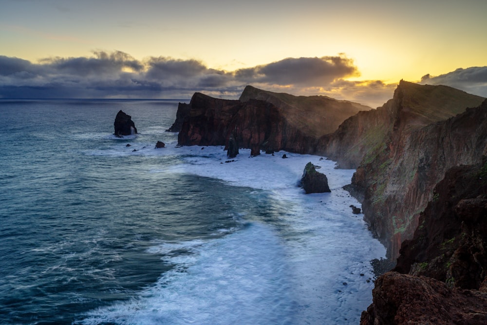 the sun is setting over the ocean and cliffs