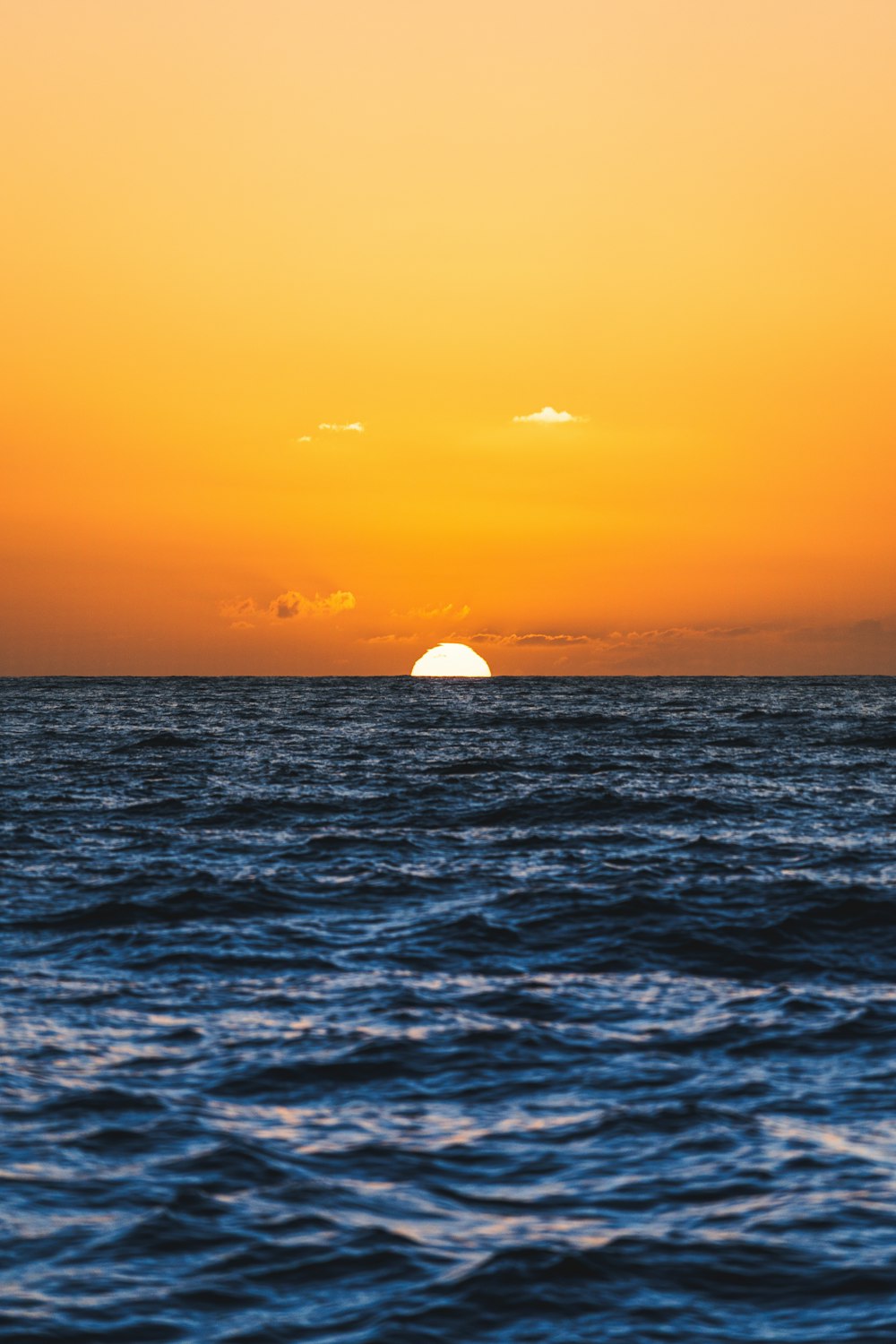Die Sonne geht über dem Meer unter, mit einem Boot in der Ferne