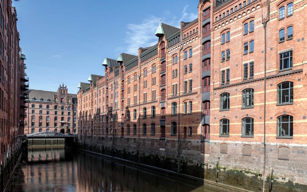 a row of red brick buildings next to a body of water