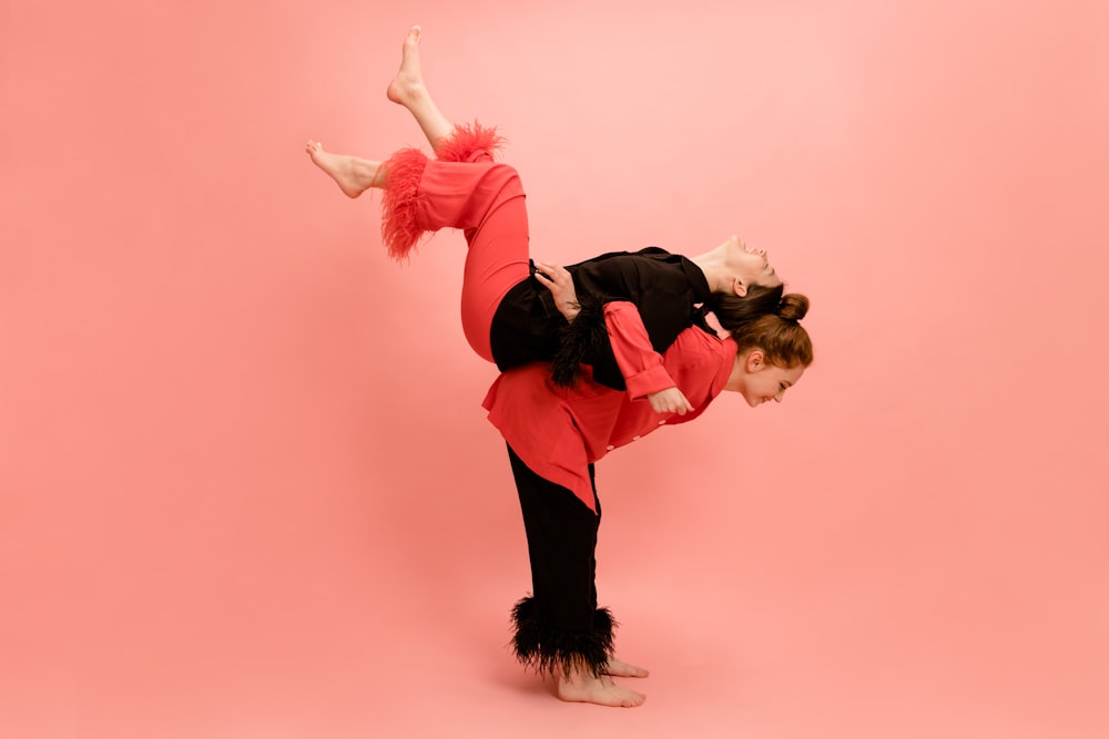a young girl doing a handstand on a pink background
