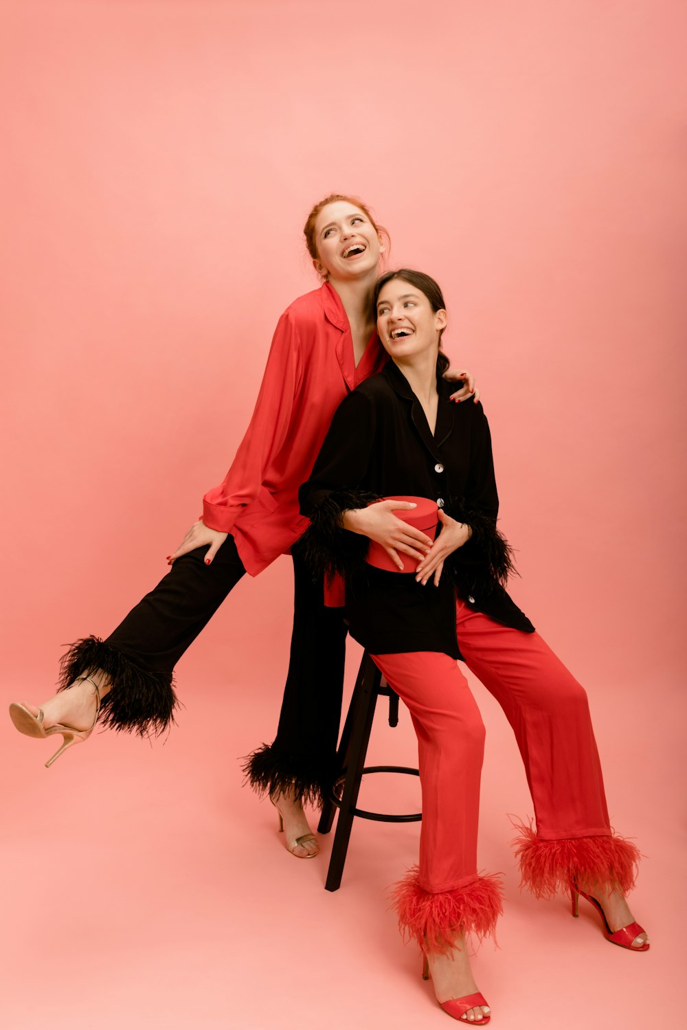 a couple of women sitting on top of a stool