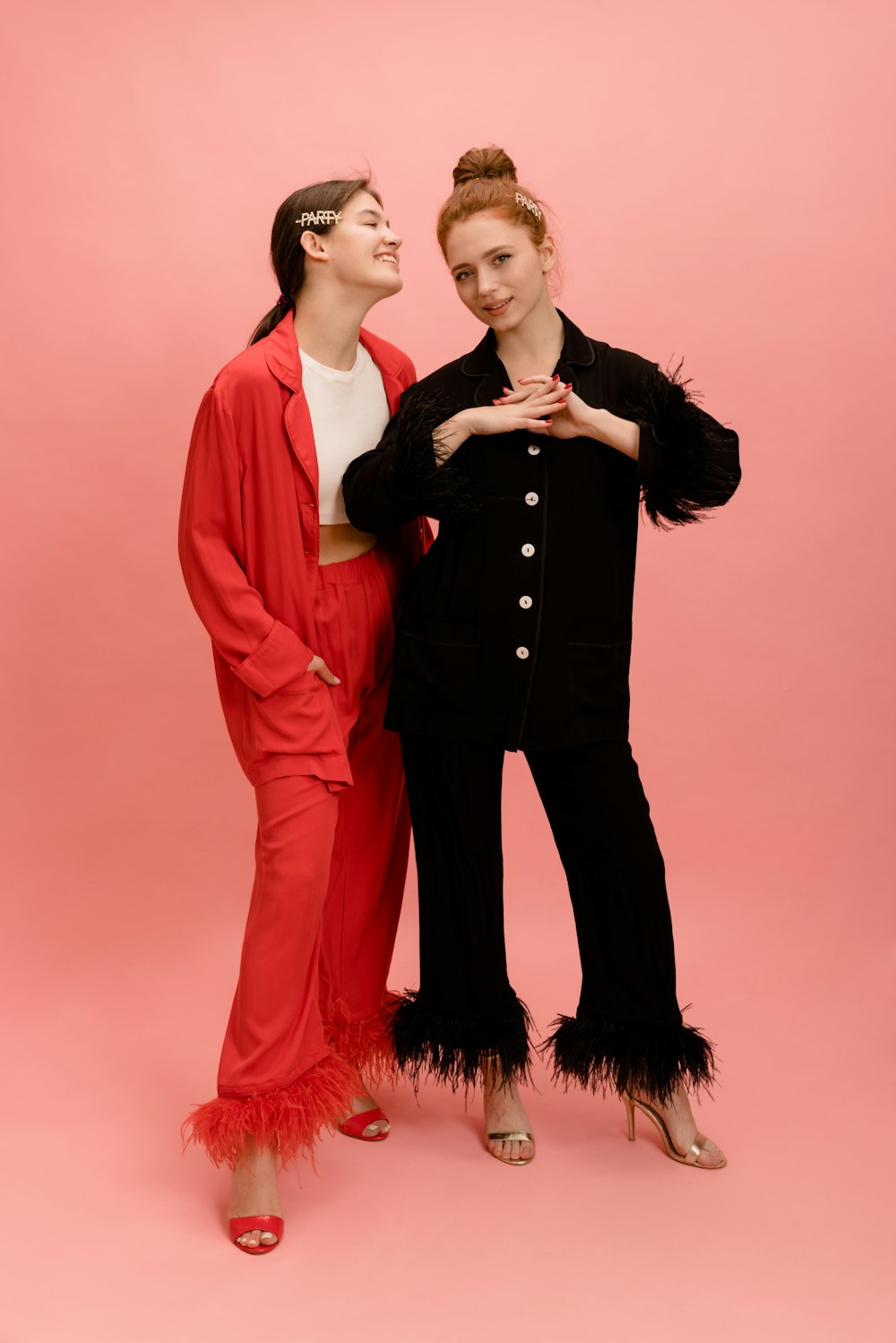 two women standing next to each other in front of a pink background