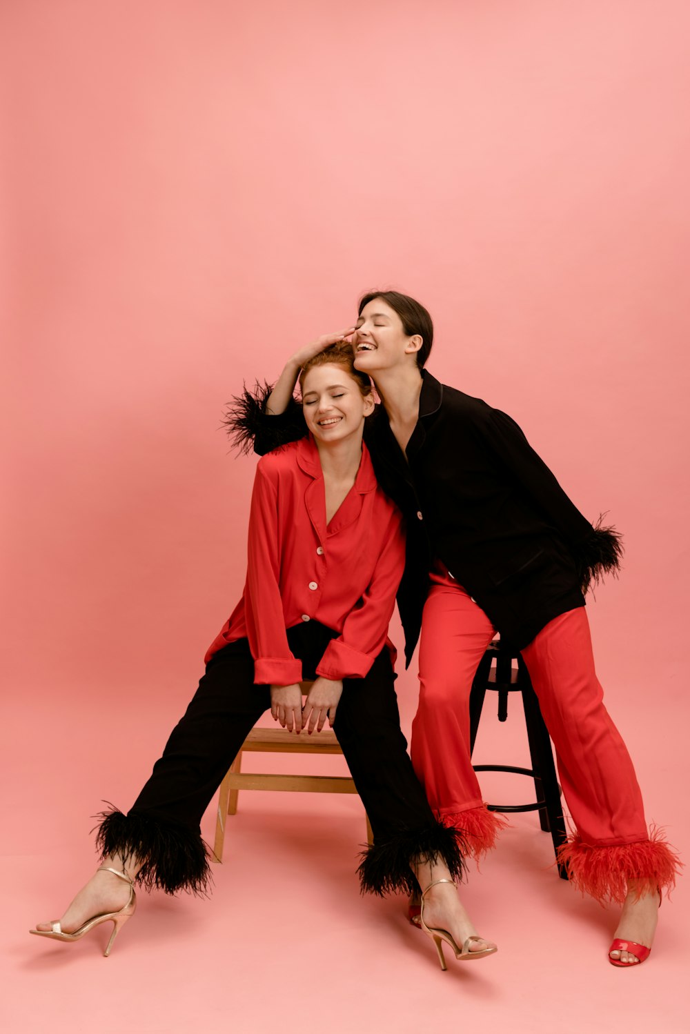 two women sitting on a stool posing for a picture