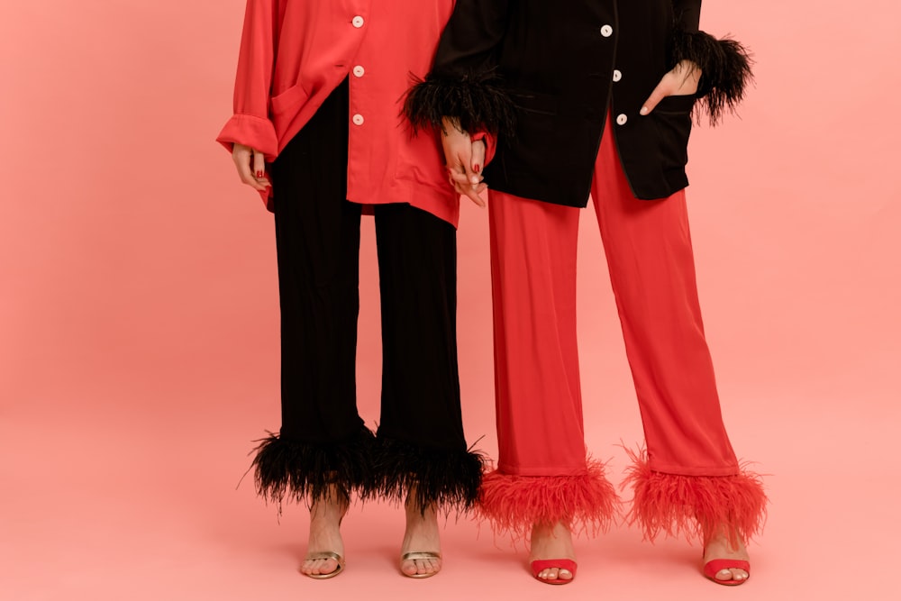 two women standing next to each other in red and black outfits