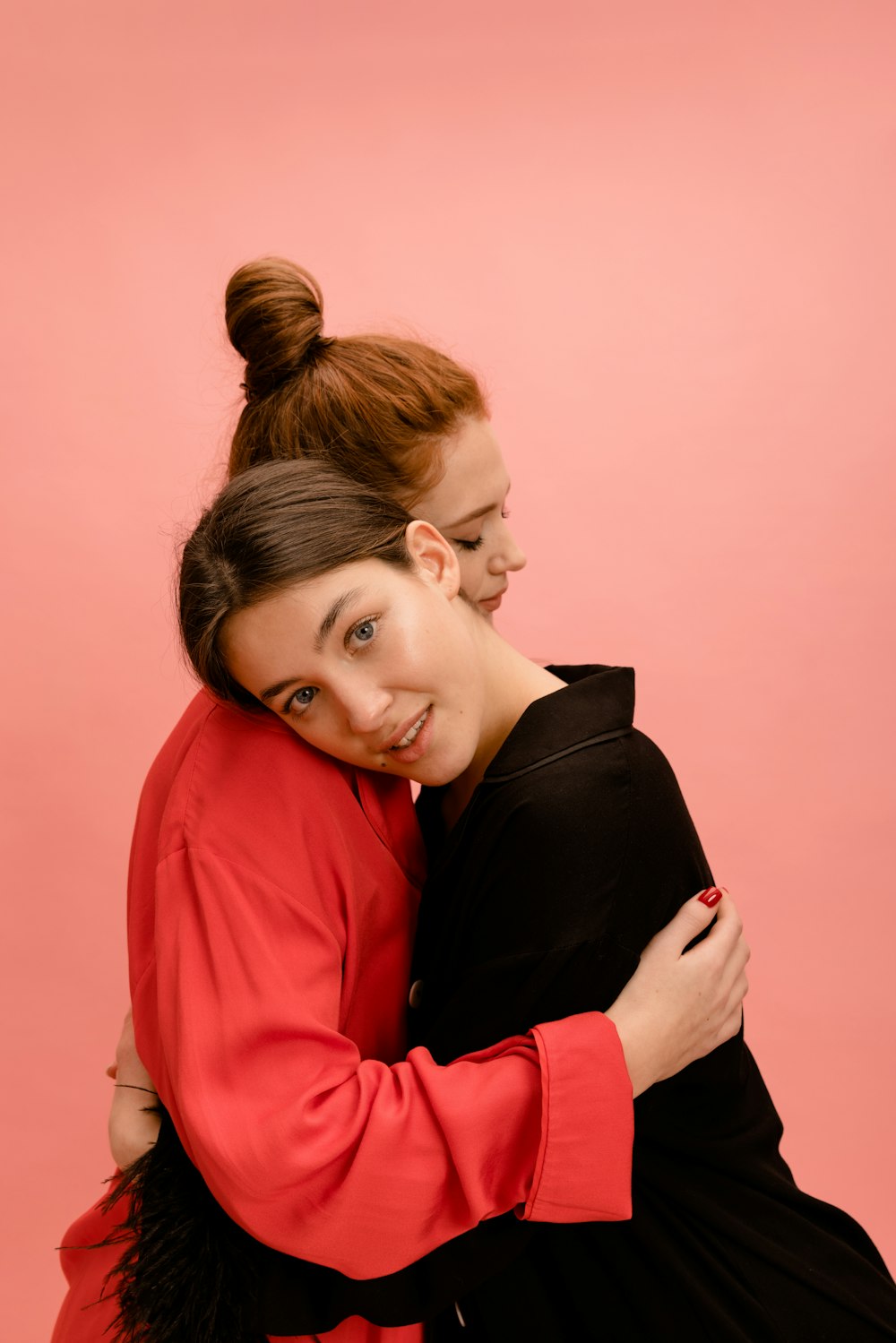 two women hugging each other in front of a pink background