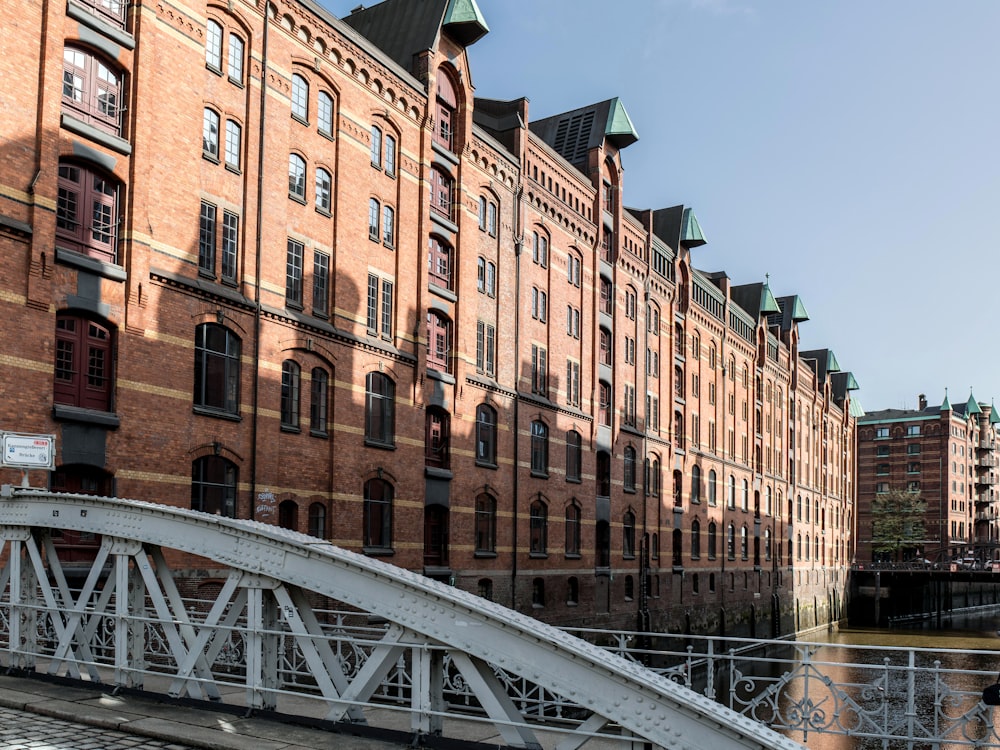 a bridge over a river in front of a large brick building