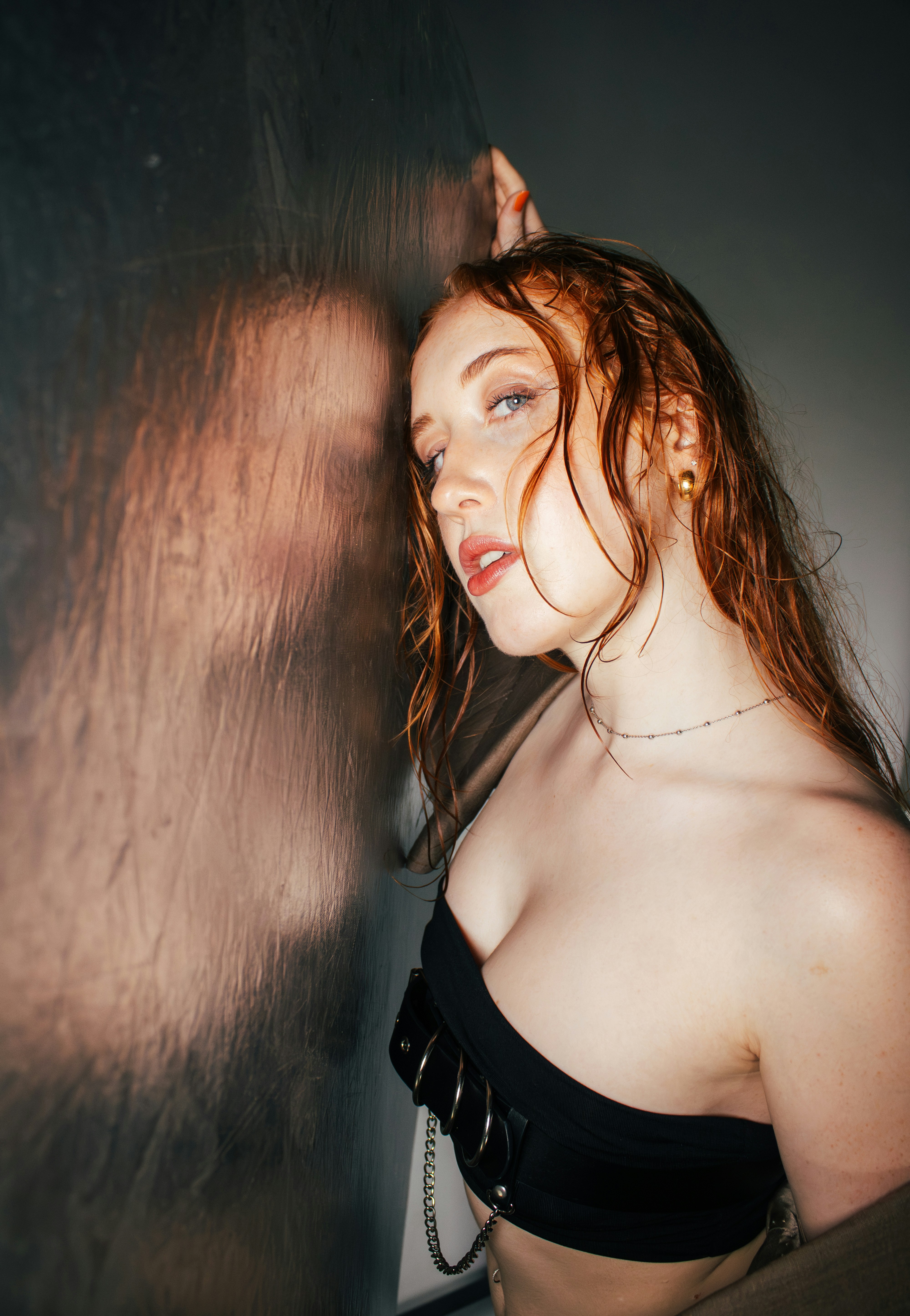 Una donna in un top nero è appoggiata a un muro