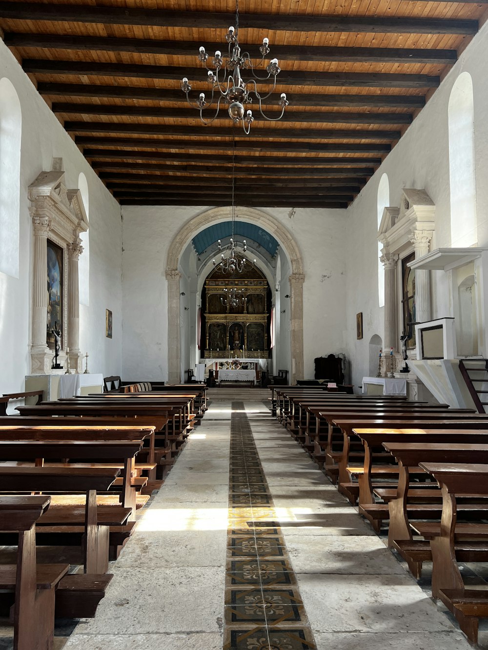 a church with pews and a chandelier hanging from the ceiling