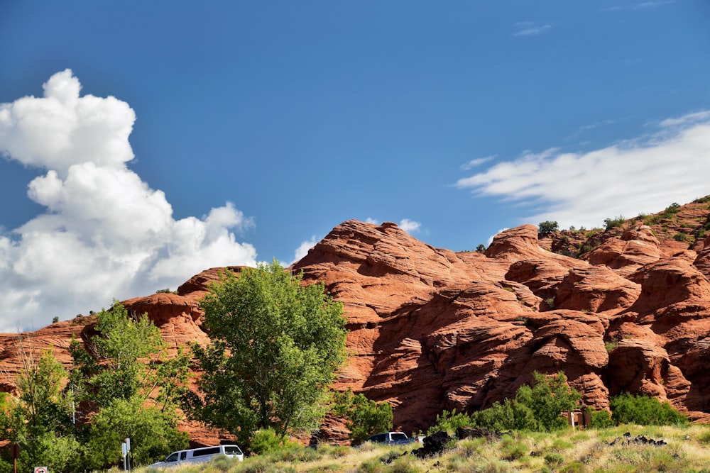 a car is parked in front of a large rock formation