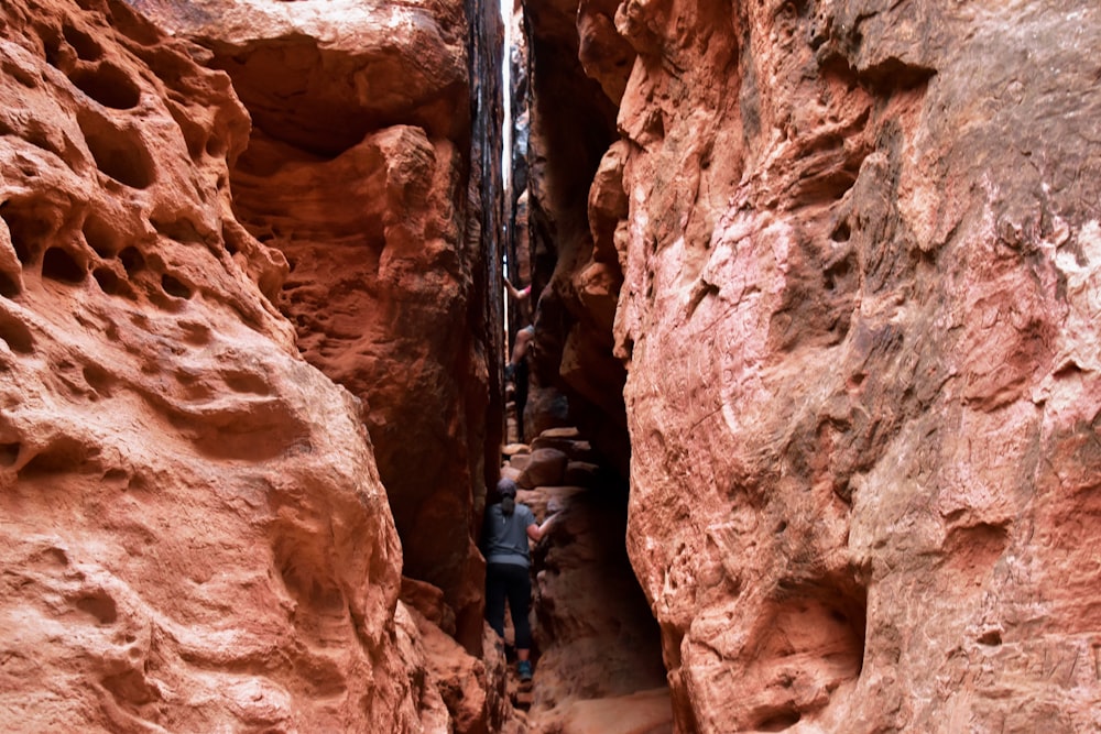 a narrow canyon with a man climbing up it