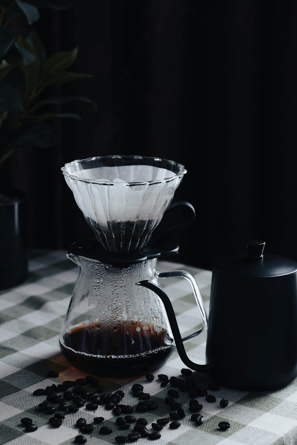 una cafetera y una taza de café sobre un mantel a cuadros