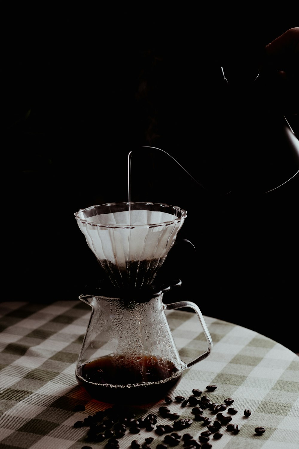 a person pours coffee into a glass pitcher
