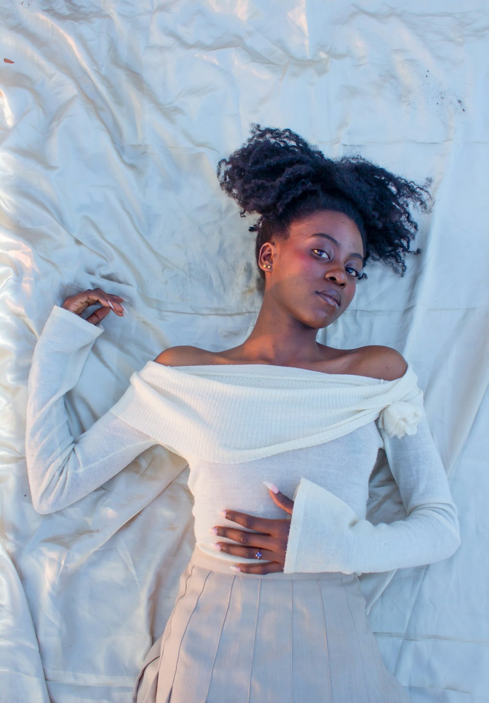 a woman laying on top of a bed covered in white sheets