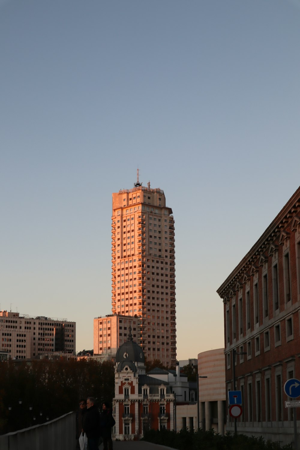 a couple of people walking down a sidewalk next to tall buildings