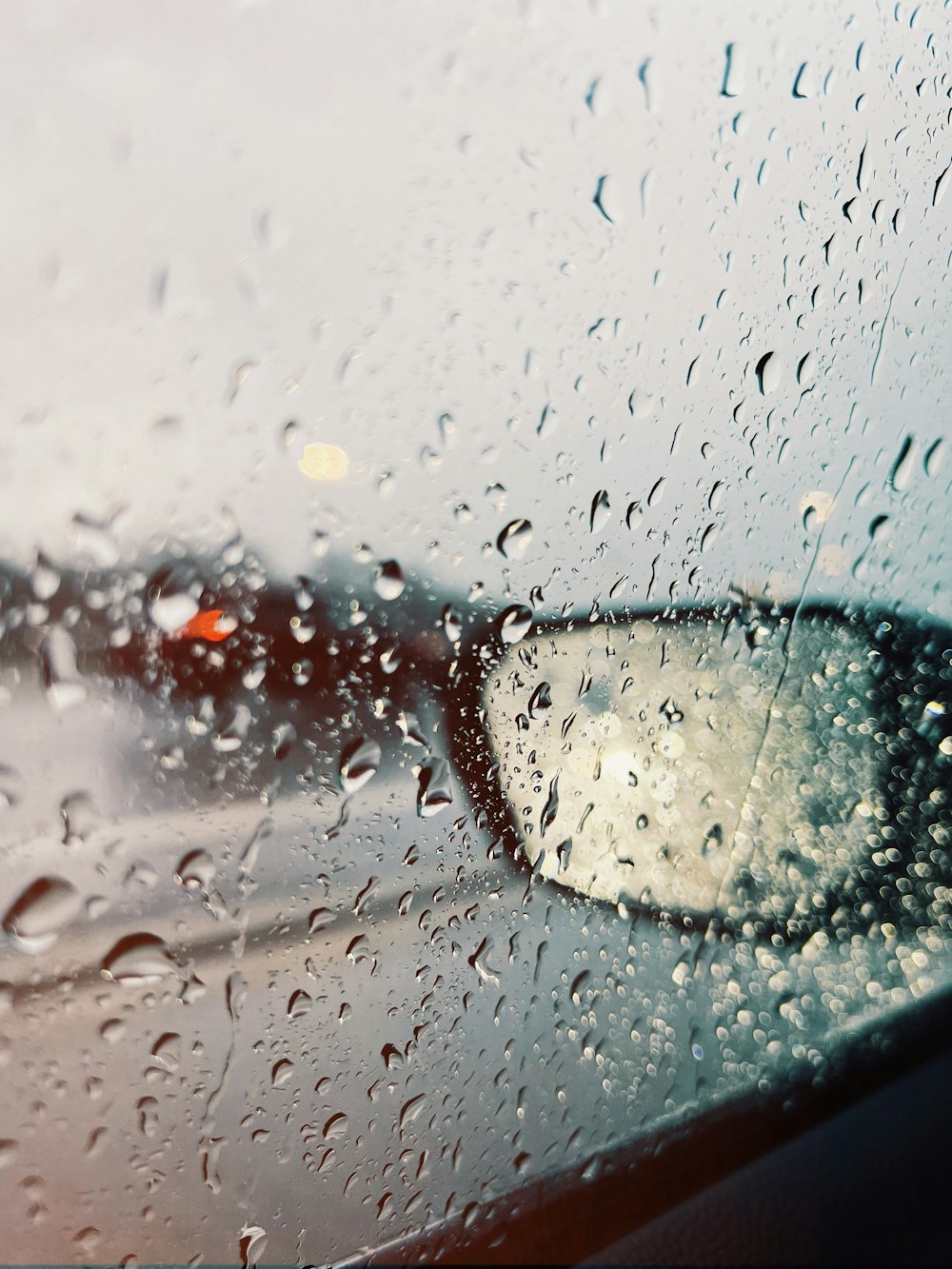 a car's side view mirror on a rainy day