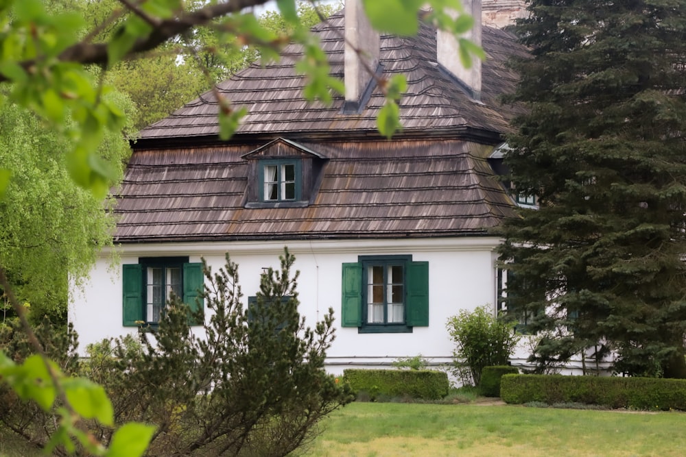 a white house with green shutters and a brown roof