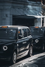 a black taxi cab driving down a street next to a tall building