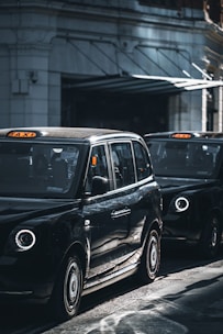 a black taxi cab driving down a street next to a tall building