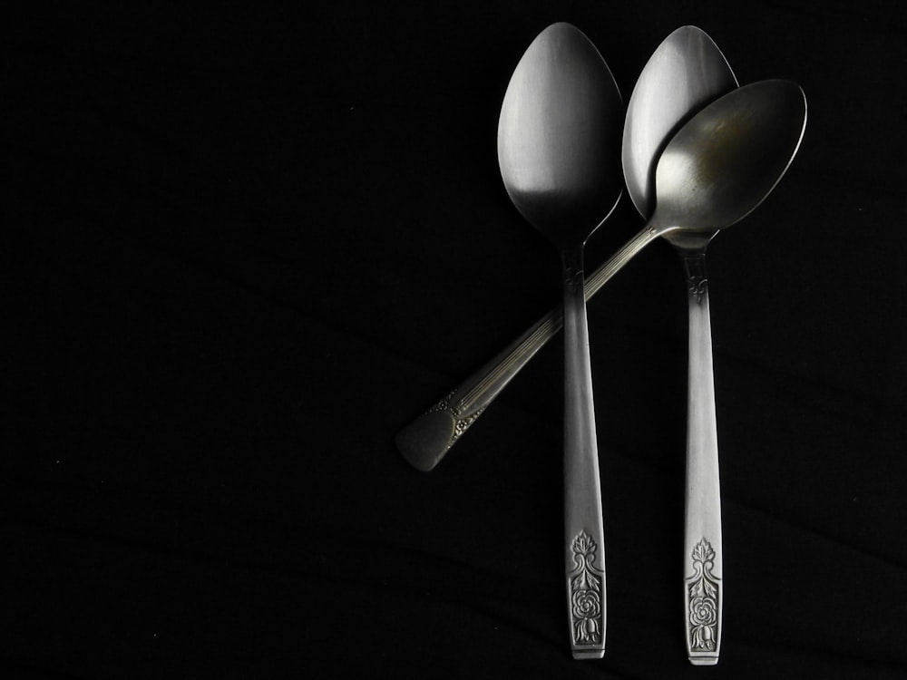 a couple of spoons sitting on top of a black table