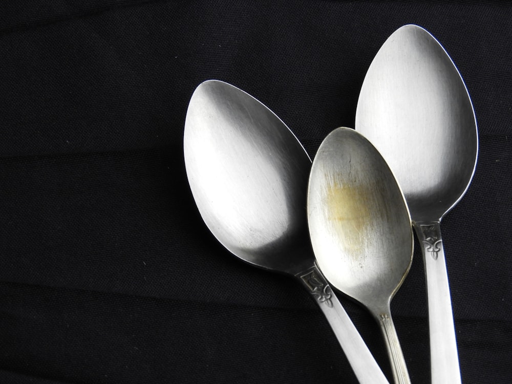 three silver spoons with a black background