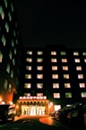 a large building lit up at night with cars parked in front of it