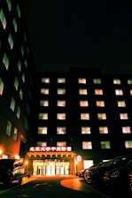 a large building lit up at night with cars parked in front of it