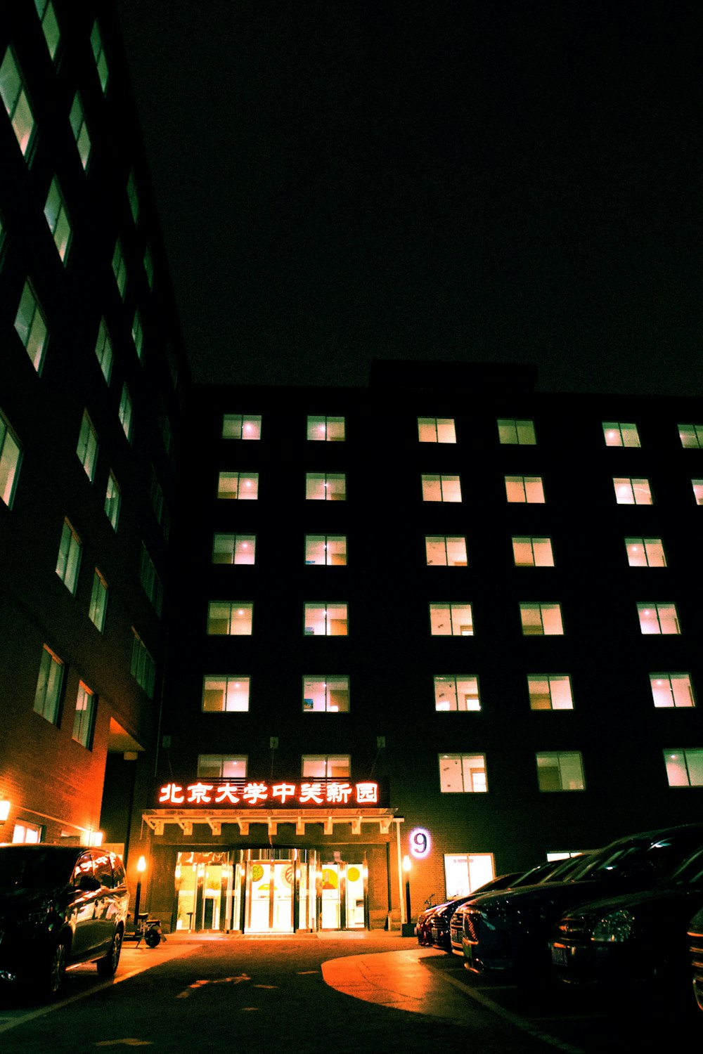 a large building lit up at night with cars parked in front of it