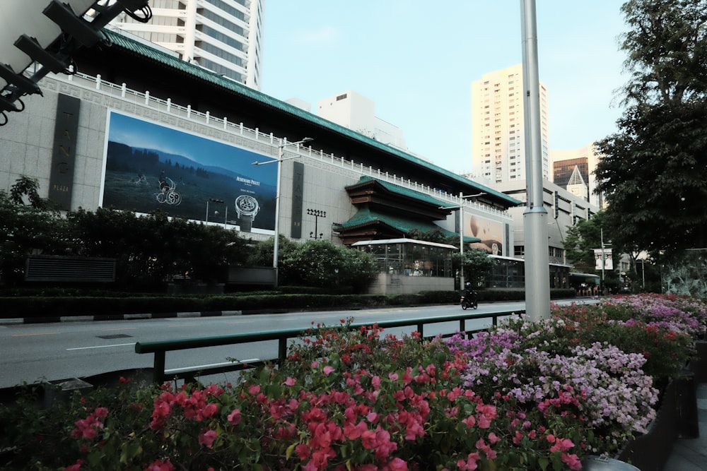 a city street with flowers and a building in the background