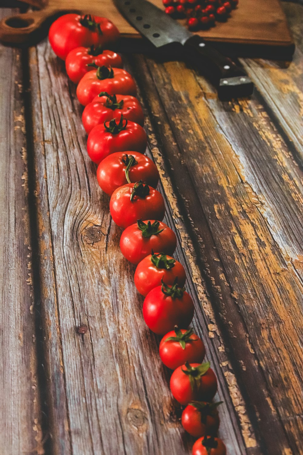 a long line of tomatoes sitting on top of a wooden table
