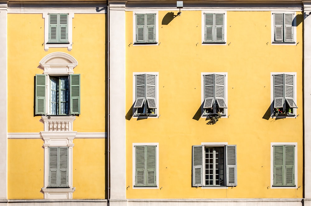 a yellow building with several windows and shutters