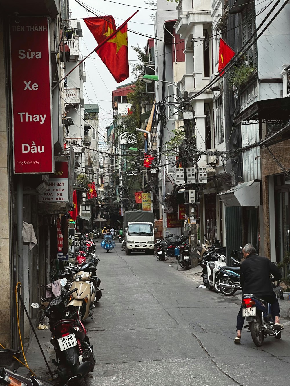 a man riding a motorcycle down a street next to tall buildings