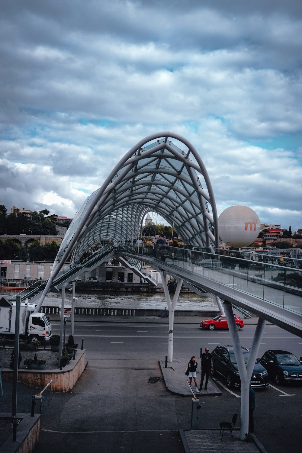 a pedestrian bridge over a busy street under a cloudy sky