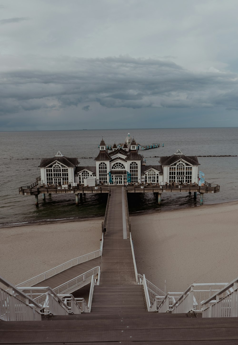 a pier on the beach with a house on it