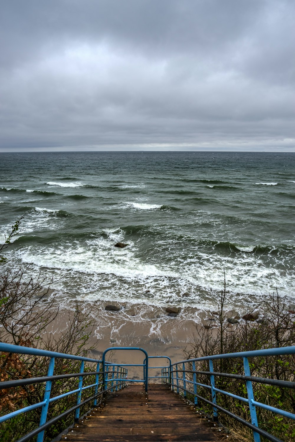 a stairway leading to the beach with waves crashing in